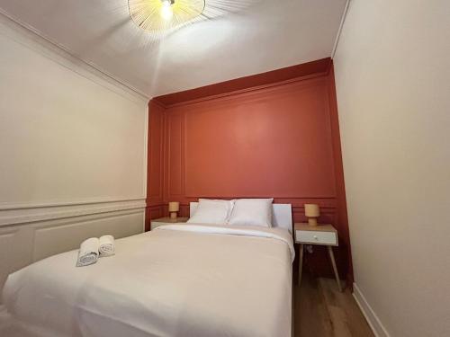 une chambre avec un grand lit blanc avec un mur rouge dans l'établissement Le Terracotta, central et intimiste, à La Celle-sous-Gouzon