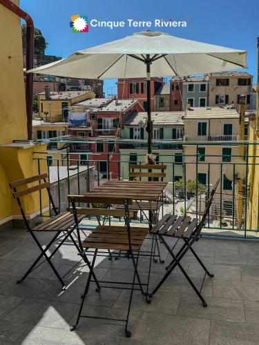 a table and chairs with an umbrella on a balcony at Ca' Bea Apartment with AC and Terrace in Vernazza