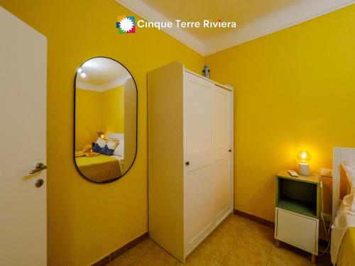 una stanza gialla con uno specchio e un letto di Ca' Bea Apartment with AC and Terrace a Vernazza