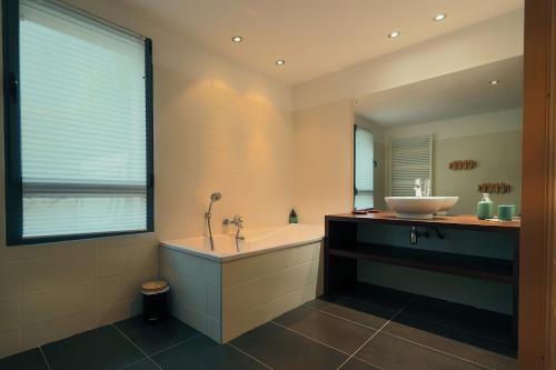 a bathroom with a bath tub and a sink at Gîte Les Neufs Lieux in Gérardmer