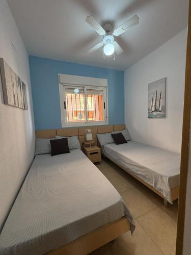 two beds in a room with a ceiling fan at APCOSTAS Torremar - Oropesa in Oropesa del Mar