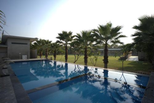 a large swimming pool with palm trees in the background at Vinn Amar Vilas by Vesta in Bharatpur