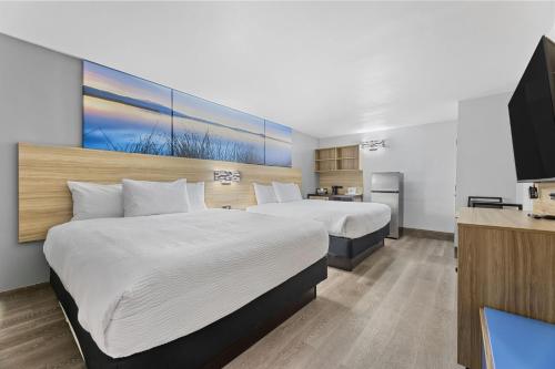 ein Hotelzimmer mit zwei Betten und einem Flachbildfernseher in der Unterkunft Days Inn & Suites by Wyndham Texas City in Texas City