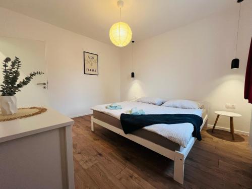 een witte slaapkamer met een bed en een tafel bij Jan Gustav Apartments in Liptovský Mikuláš