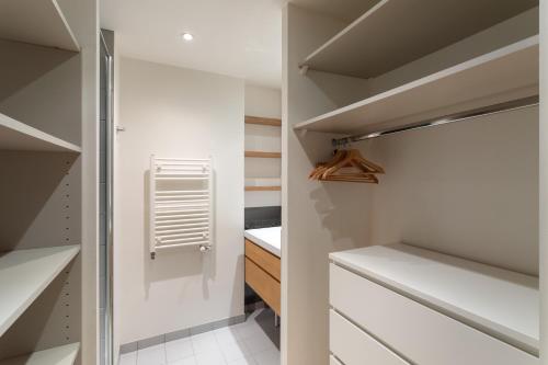 einen begehbaren Kleiderschrank mit weißen Wänden und weißen Schränken in der Unterkunft Le Rock Fish - Quelques minutes de la plage in Dinard