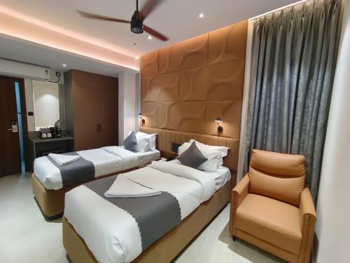 a hotel room with two beds and a chair at 23 Urban Suites, Hitech City in Hyderabad