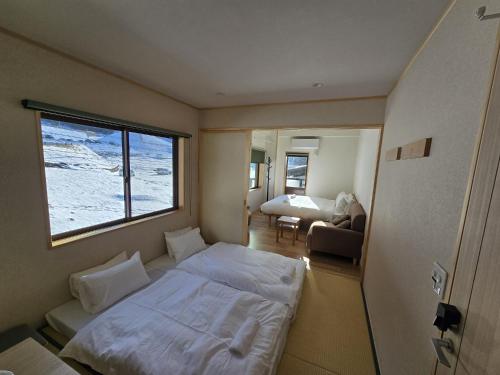 ein kleines Zimmer mit einem Bett und einem Fenster in der Unterkunft Schanze Nozawa in Nozawa Onsen