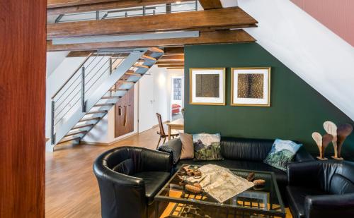 a living room with a black couch and a staircase at Apparthotel Bad Schandau by STEIGER Hotels in Bad Schandau