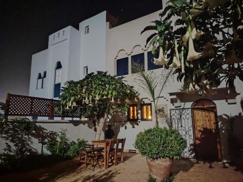 een wit gebouw met een tafel en stoelen ervoor bij L'îlot in Sidi Ifni