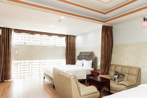 ein Hotelzimmer mit einem Bett und zwei Stühlen in der Unterkunft Khánh Ly Hotel - 庆丽酒店 in Ga Tân Thiết