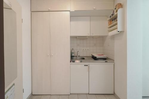a white kitchen with white cabinets and a sink at Seehütte 004 in Cuxhaven
