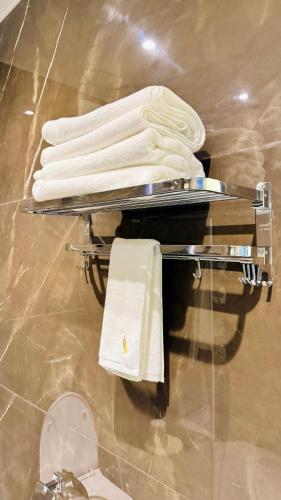 a rack with white towels and a toilet in a bathroom at Pheonix Luxury Inn in Akolia