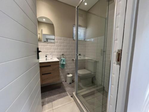 a bathroom with a shower and a toilet and a sink at Sting-ray Cottage in Port Edward