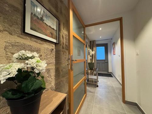 einen Flur mit einer Tür und einer Vase aus Blumen in der Unterkunft Le Kandinsky, moderne et spacieux in La Celle-sous-Gouzon