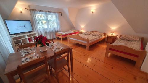 a living room with two beds and a table and a television at Villa Poronianka in Poronin