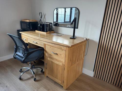 a wooden desk with a mirror and a chair at The Guest Room in Aldridge