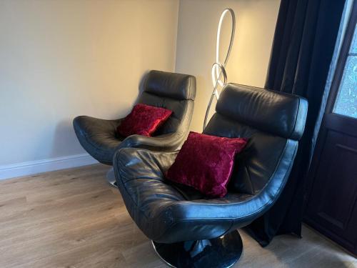 zwei Ledersessel mit roten Kissen in einem Zimmer in der Unterkunft The Guest Room in Aldridge