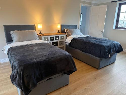 a bedroom with two beds and a table with two lamps at The Guest Room in Aldridge