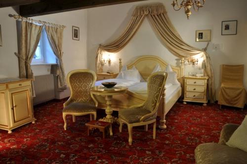 a bedroom with a bed and a table and chairs at Hotel Ansitz Kandelburg in Mühlbach