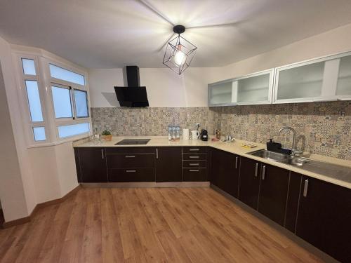 een keuken met bruine kasten, een wastafel en een raam bij Casa Mares in Teror