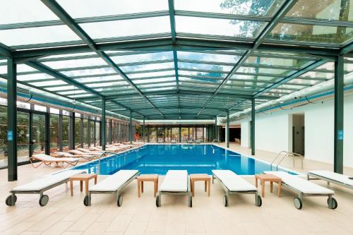 a pool with tables and benches in a building at BIO Hotel - Hotel Quinta da Serra in Estreito de Câmara de Lobos