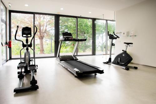 a gym with three exercise bikes in a room with windows at BIO Hotel - Hotel Quinta da Serra in Estreito de Câmara de Lobos