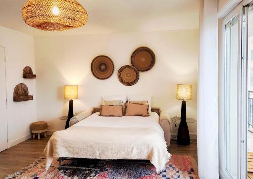 - une chambre avec un lit blanc et 2 assiettes murales dans l'établissement Calme et verdure à Poissy 50 m2 parking terrasse, à Poissy