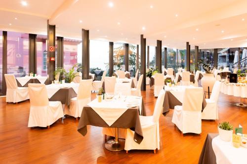 a restaurant with white tables and chairs and windows at BIO Hotel - Hotel Quinta da Serra in Estreito de Câmara de Lobos