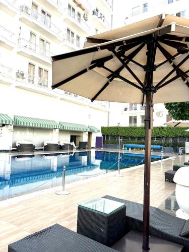 a table with an umbrella next to a swimming pool at The Amerin Inn & Suites , Gomti Nagar Lucknow in Lucknow