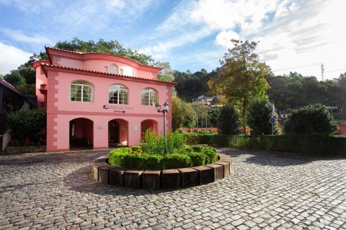 a pink building with a courtyard in front of it at BIO Hotel - Hotel Quinta da Serra in Estreito de Câmara de Lobos