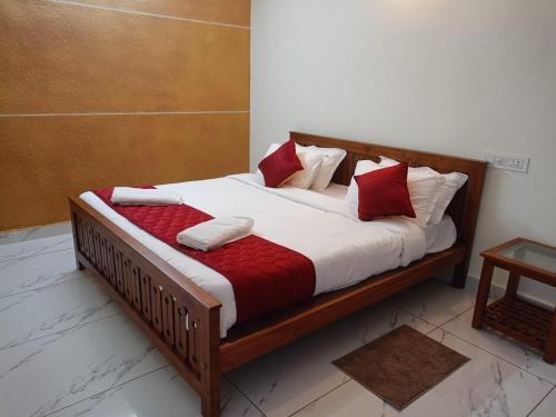 een houten bed met rode en witte kussens erop bij Valley De Hills Farm Villa in Attappādi