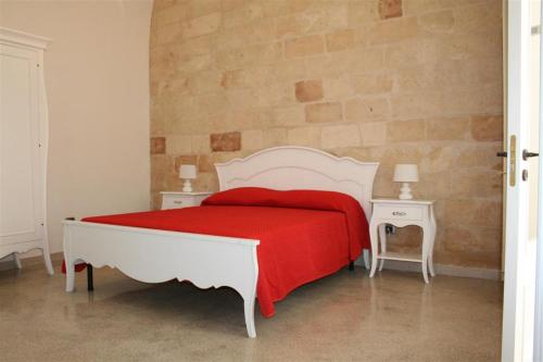 een slaapkamer met een wit bed en een rode deken bij Corte Lecciso in Leverano