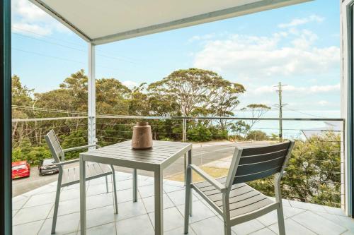 a table and chairs on a balcony with a view of the ocean at Seahaven - pet-friendly retreat near Hyams Beach in Hyams Beach