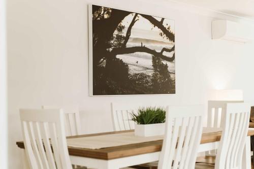 a dining room table and chairs with a picture on the wall at Seahaven - pet-friendly retreat near Hyams Beach in Hyams Beach