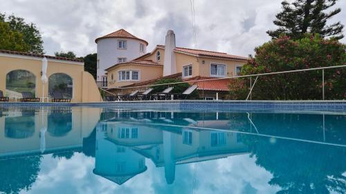 a house with a swimming pool in front of it at Quinta do Cabo Guesthouse in Sintra