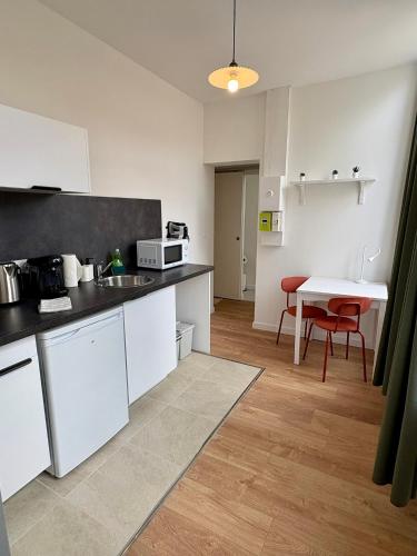 a kitchen with white cabinets and a table with red chairs at Azur 2 - Gare de Roubaix in Roubaix