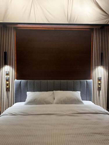 a large bed with a wooden headboard and two lights at Princess Milena in London
