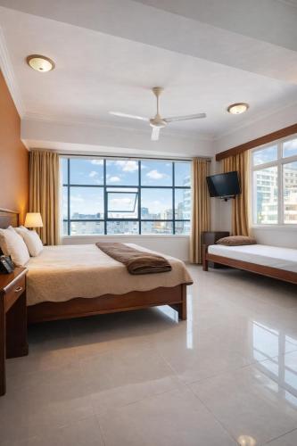ein Schlafzimmer mit zwei Betten und einem großen Fenster in der Unterkunft Rainbow Hotel in Daressalam
