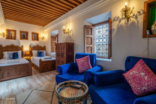 a living room with blue chairs and a bed and a window at Riad La Sultana in Chefchaouene