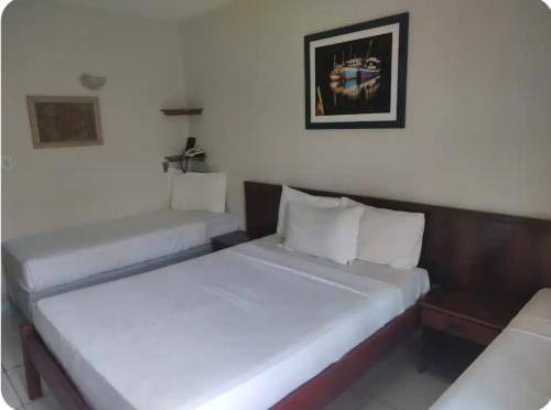 two beds in a hotel room with white walls at Portobello in Porto Seguro