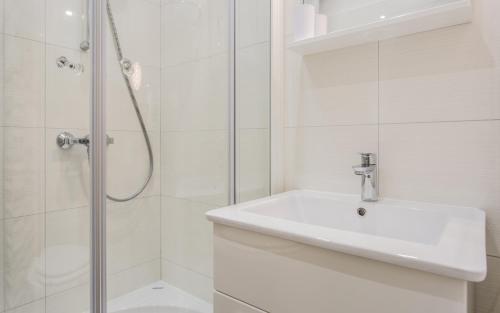 een witte badkamer met een wastafel en een douche bij Sunrise Apartment Risika in Risika