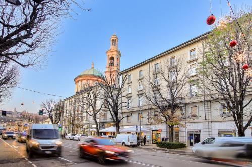 ein Gebäude mit einem Uhrturm auf einer Straße mit Autos in der Unterkunft Center of Bergamo BGYnn Le Grazie in Bergamo