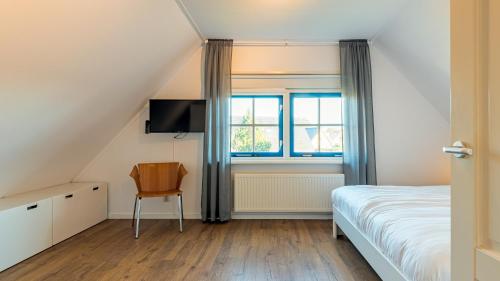 een slaapkamer met een bed, een stoel en een raam bij De Lepelaer in Schoorl