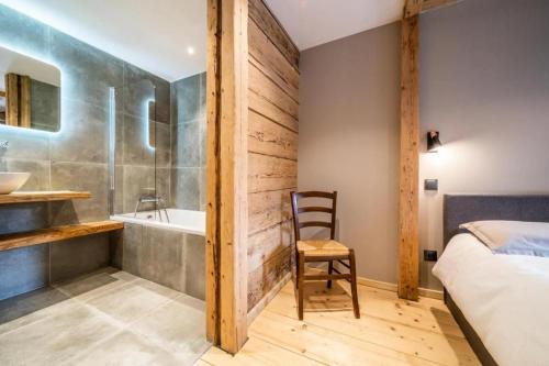 a bedroom with a tub and a bed and a chair at LA FERME D'AGATHE in Abondance