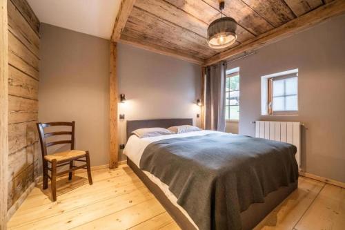 a bedroom with a large bed and a chair at LA FERME D'AGATHE in Abondance