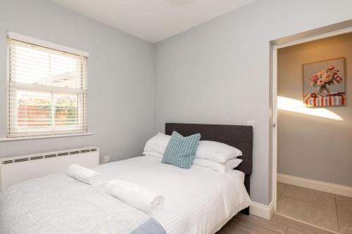 ein Schlafzimmer mit einem Bett mit weißer Bettwäsche und einem Fenster in der Unterkunft Nr 8 - Modern 2 Bed Flat - WiFi - Town Centre - Parking in Bedford