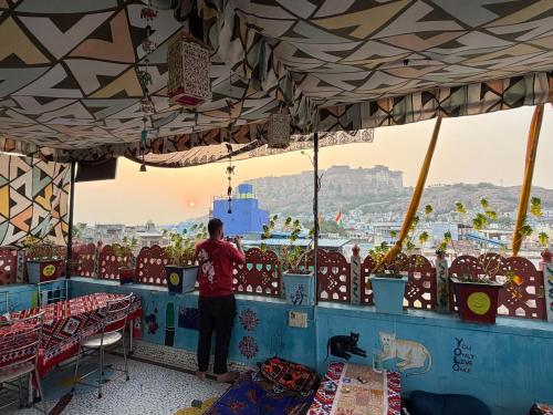 a man standing at a counter looking out at the city at Musa's Homestay in Jodhpur