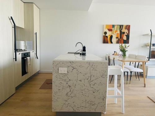 a kitchen with a counter and a table with chairs at Macquarie Park Station,2BR, 4 Beds,Parking,Swimming Pool in Sydney