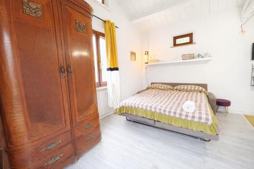 a bedroom with a bed and a large wooden cabinet at fattoria Coppetella Cemani in Molino dʼAgugliano