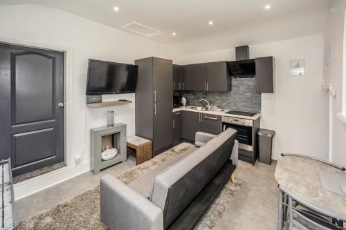 a living room with a couch and a kitchen at Cottage hide-out in Kirkheaton